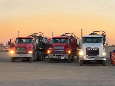 Image of three Equipment Transport trucks representing our fleet of hundreds of trucks and drivers. Equipment Transport is a leading provider of midstream logistics solutions.