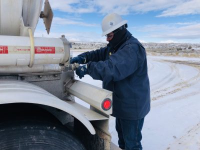 Image of an Equipment Transport employee performing a safety check on a truck. Equipment Transport is a leading provider of midstream logistics solutions.